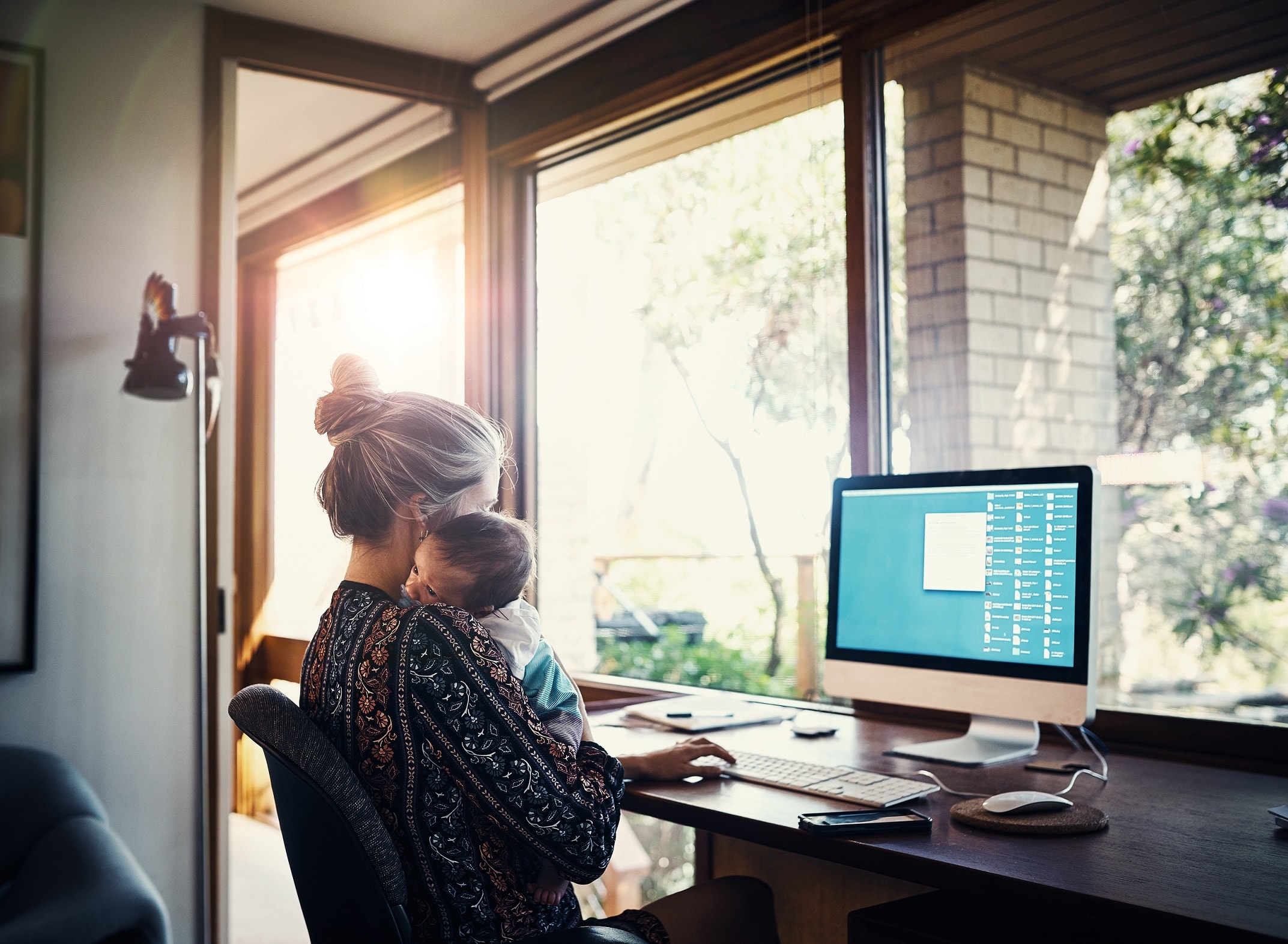 mother and baby at home sitting at a desk with computer